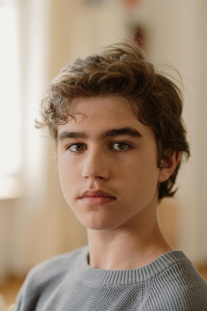 Portrait of a serious teenage boy in soft natural light, highlighting his contemplative expression.